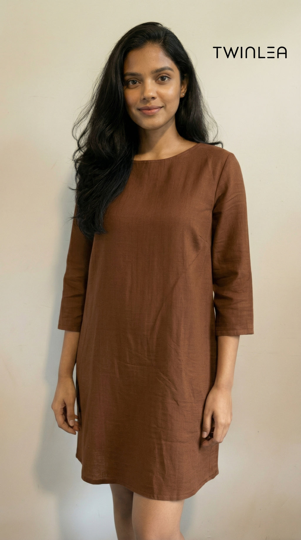Model wearing a brown dress with a plain background