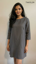 Model wearing a gray dress with long sleeves against a plain background